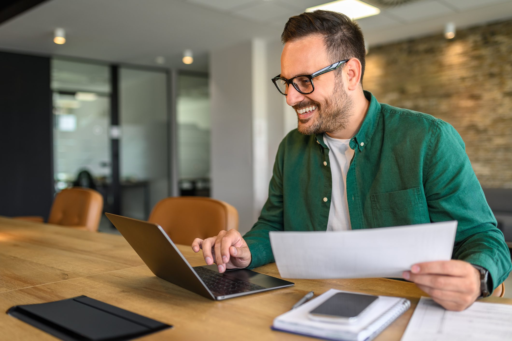 Man smiling while working on a laptop.