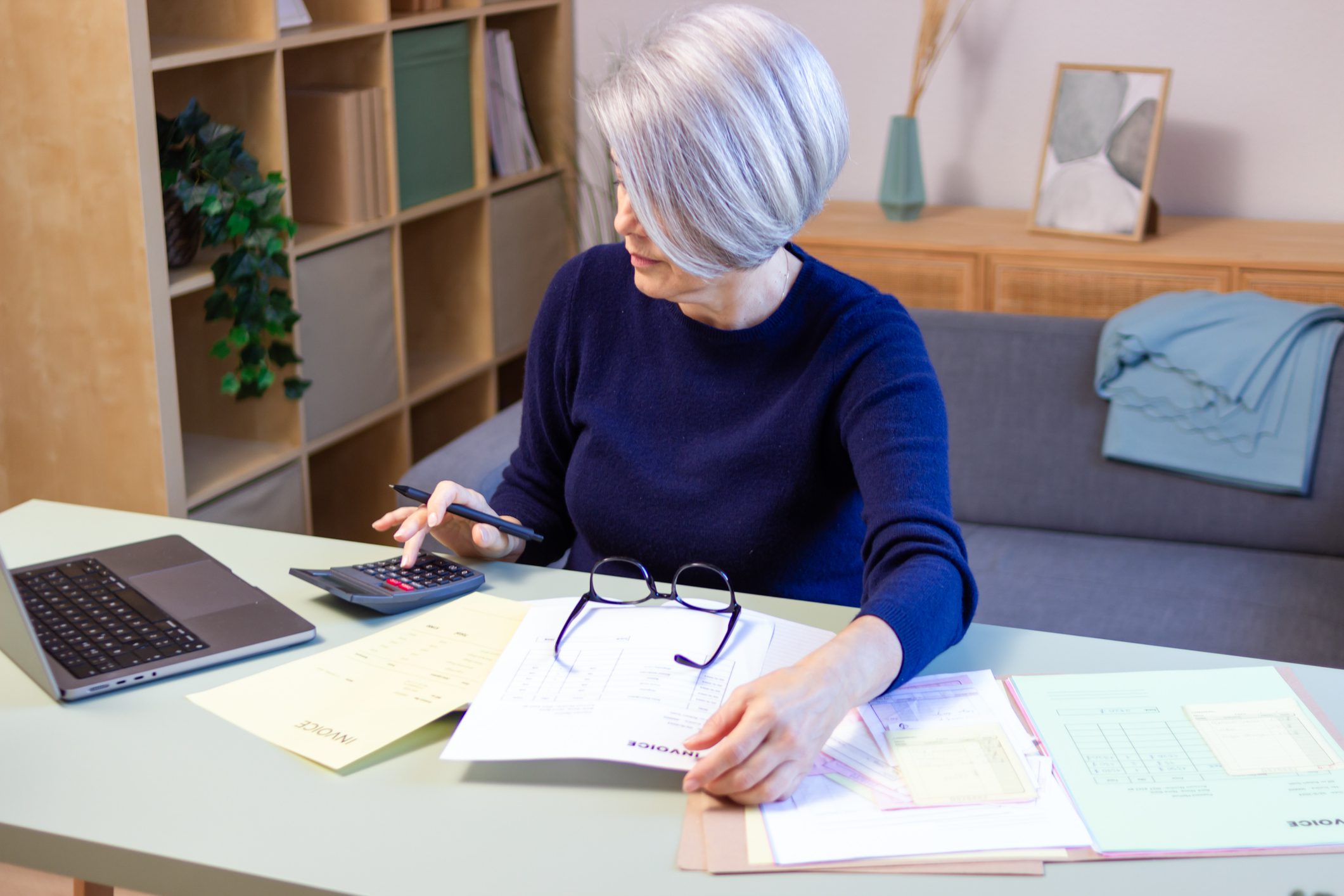 Person calculating with papers and laptop.